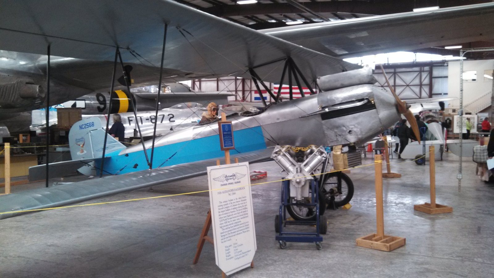 A silver and blue Long Wing Eaglerock biplane in a museum hangar, a different airplane of the same type as the Collection's N5910.