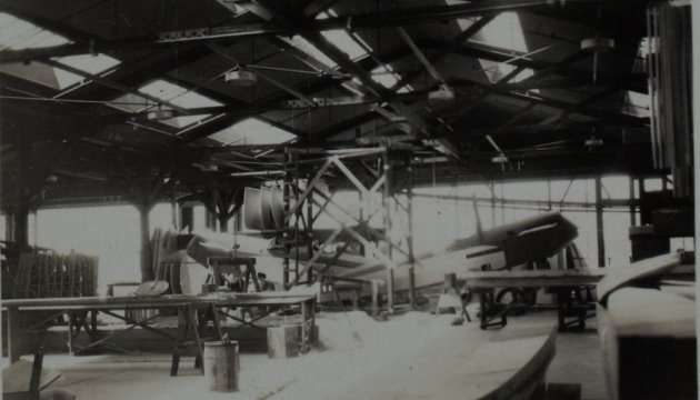 Black-and-white photograph inside an Alexander factory building in the late 1920s, with airframes under construction.